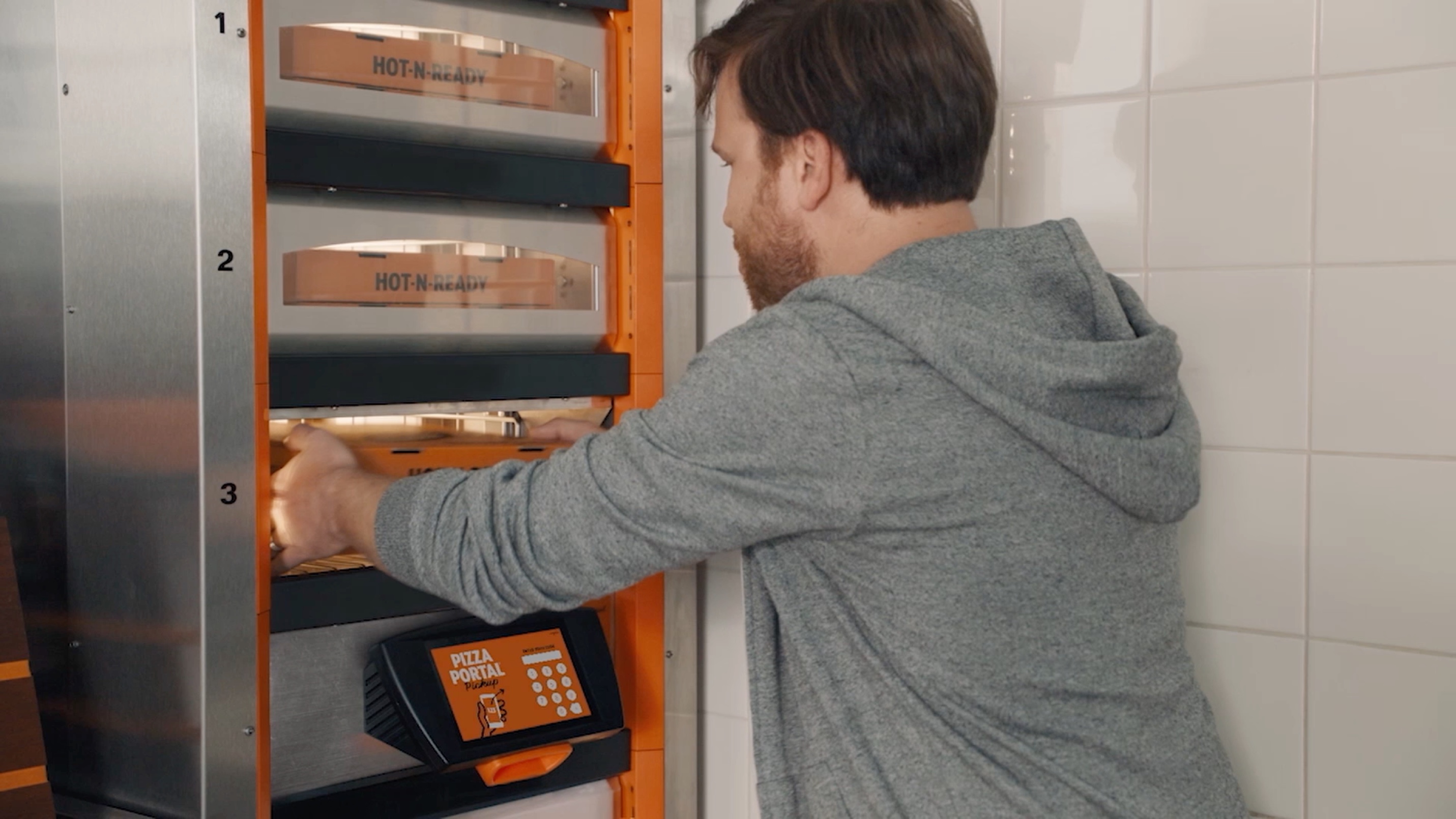 Man taking his Little Caesars pizza out of the pizza warmer.