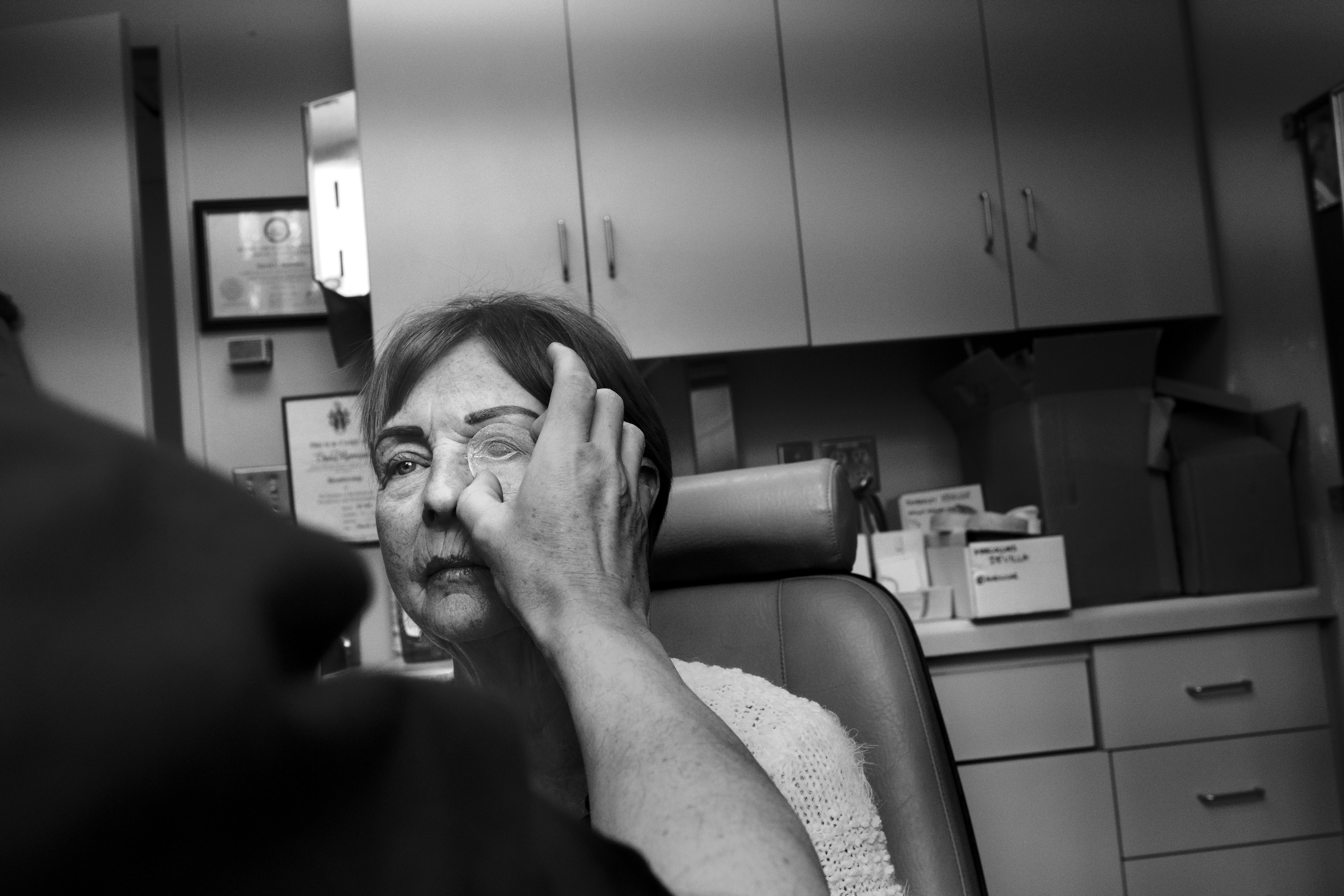 A doctor holding a patch up to a patient's eye.