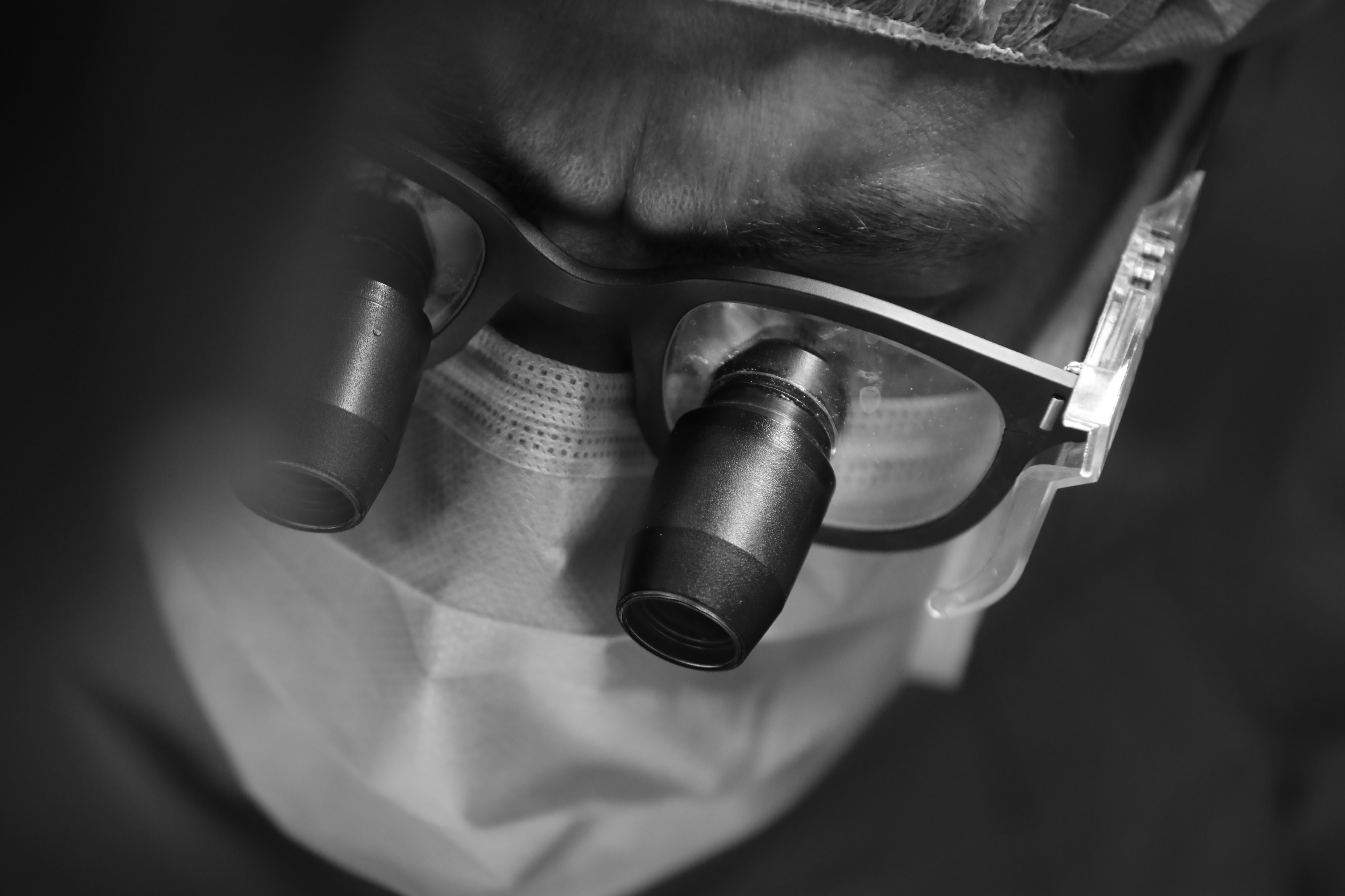 A surgeon wearing surgical loupes and mask