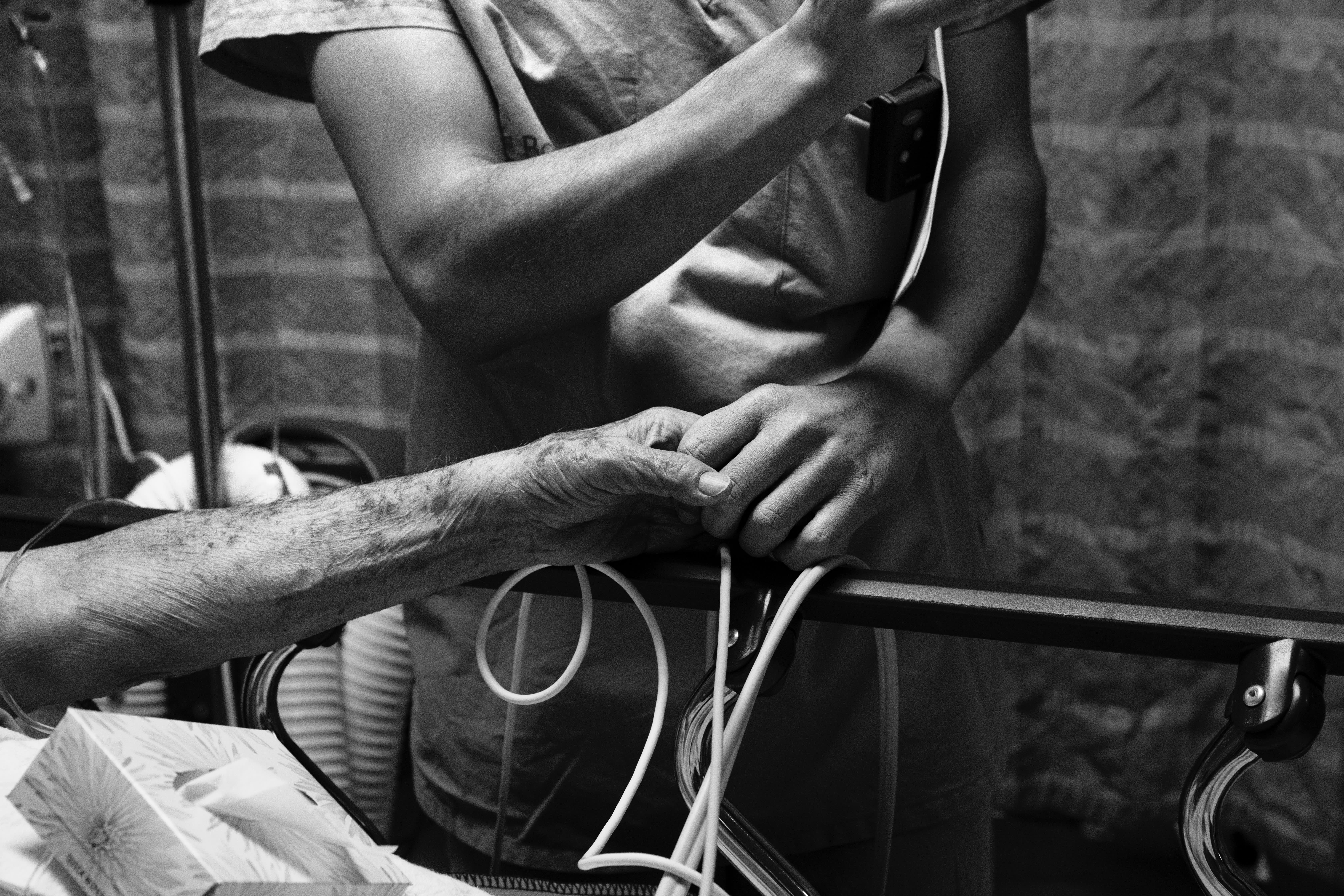 A nurse holding an older patient's hand.