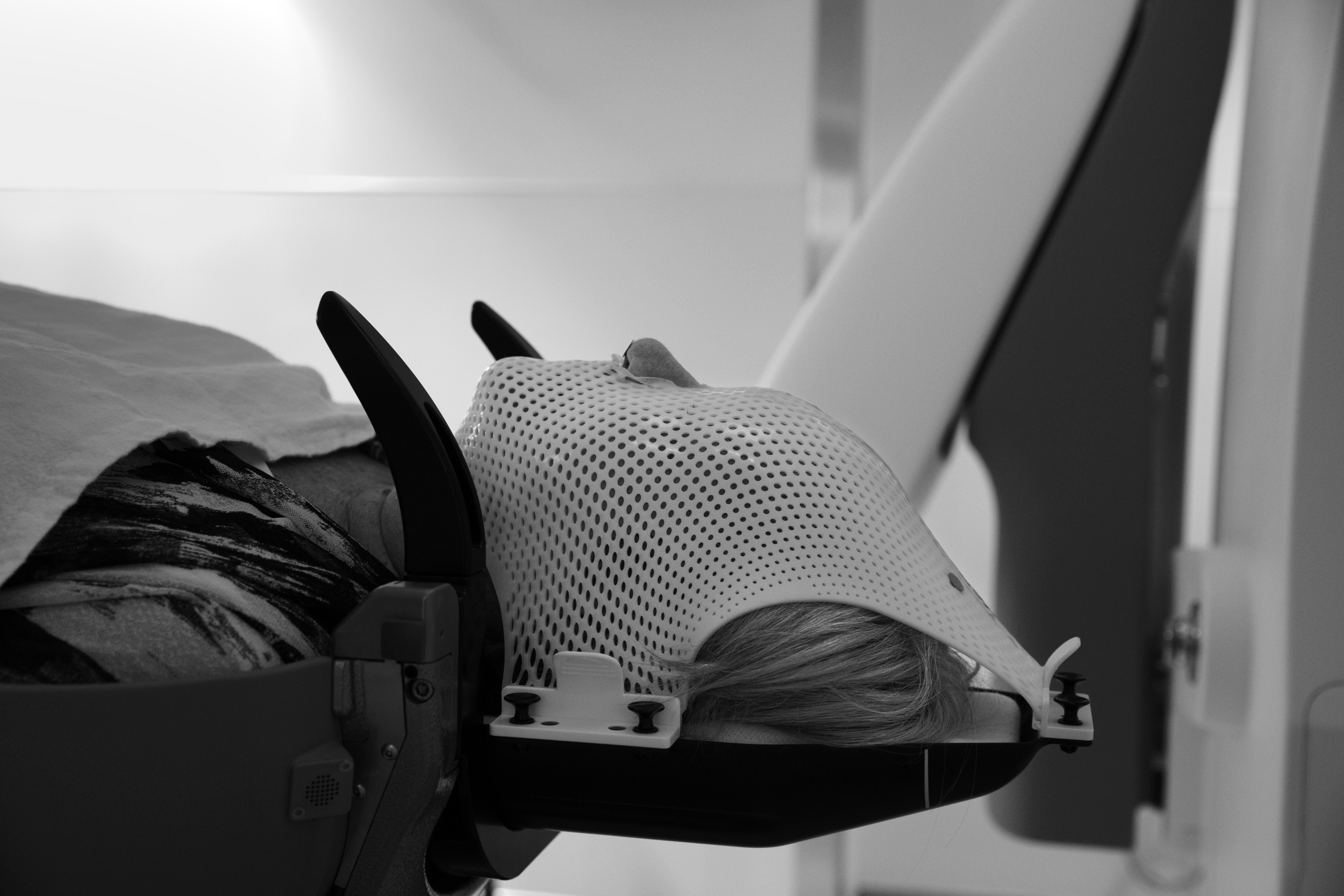 A patient lying down and wearing a radiotherapy mask.