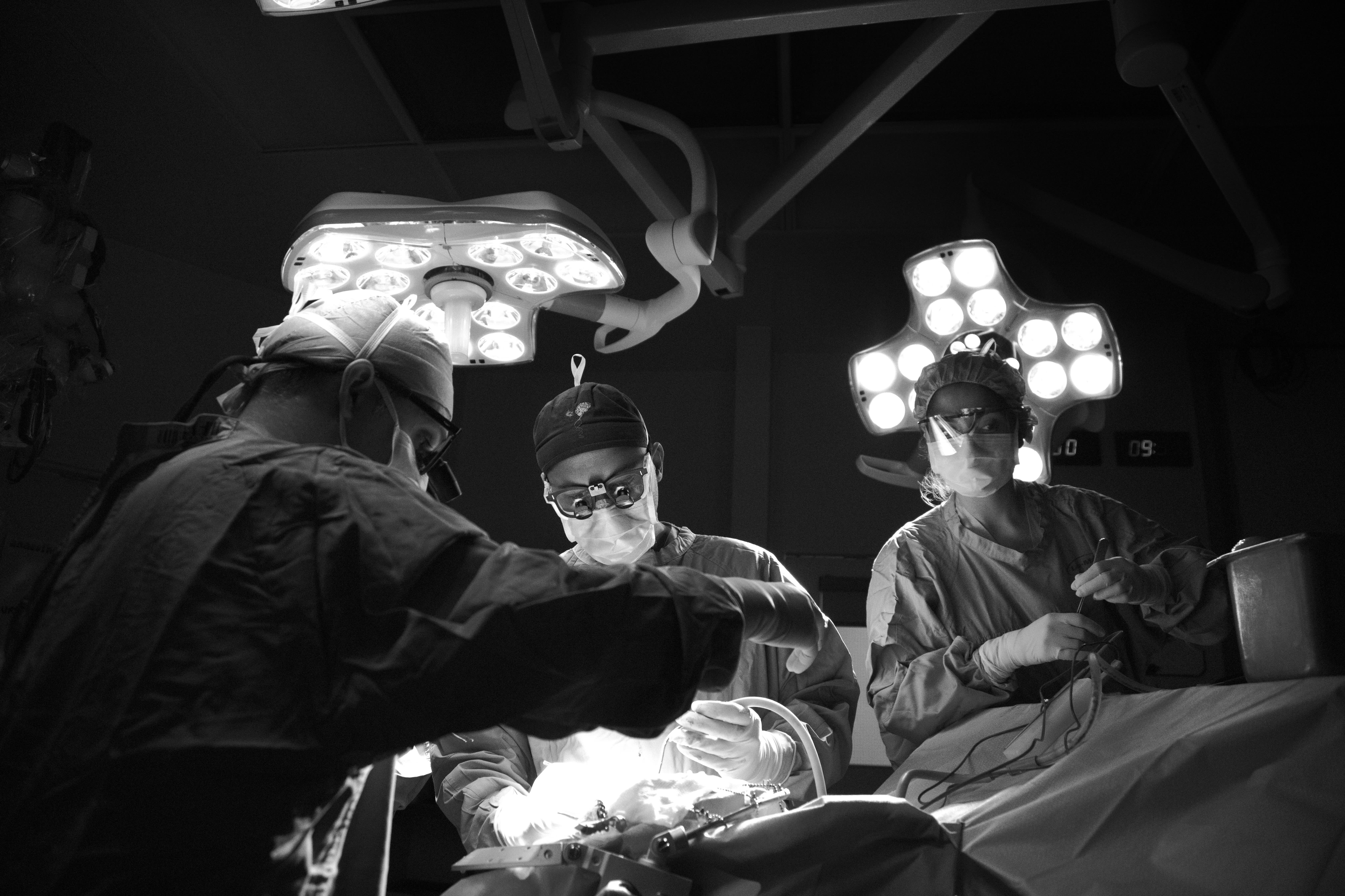A surgeon and two nurses performing surgery.
